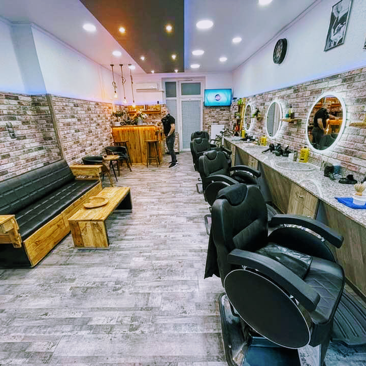 Salon von Mos's Herrenfriseur mit Barberstühlen und beleuchteten Spiegeln